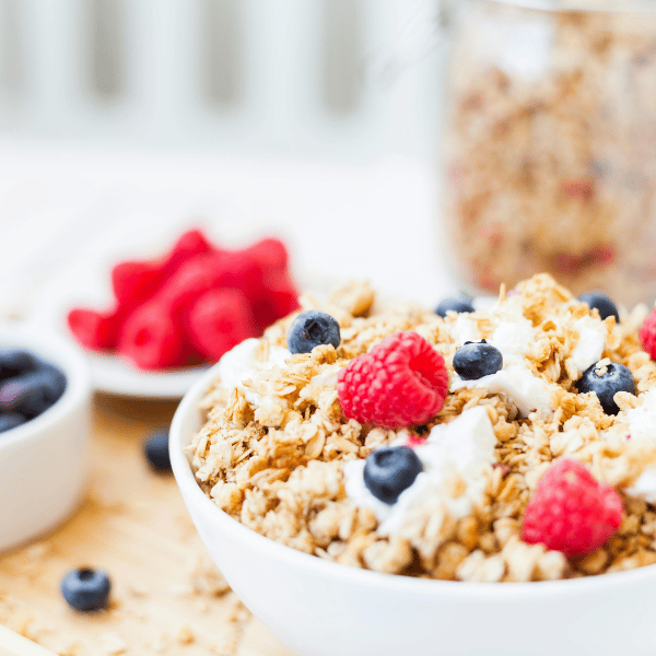 bowl of yogurt with granola, raspberries, and blueberries